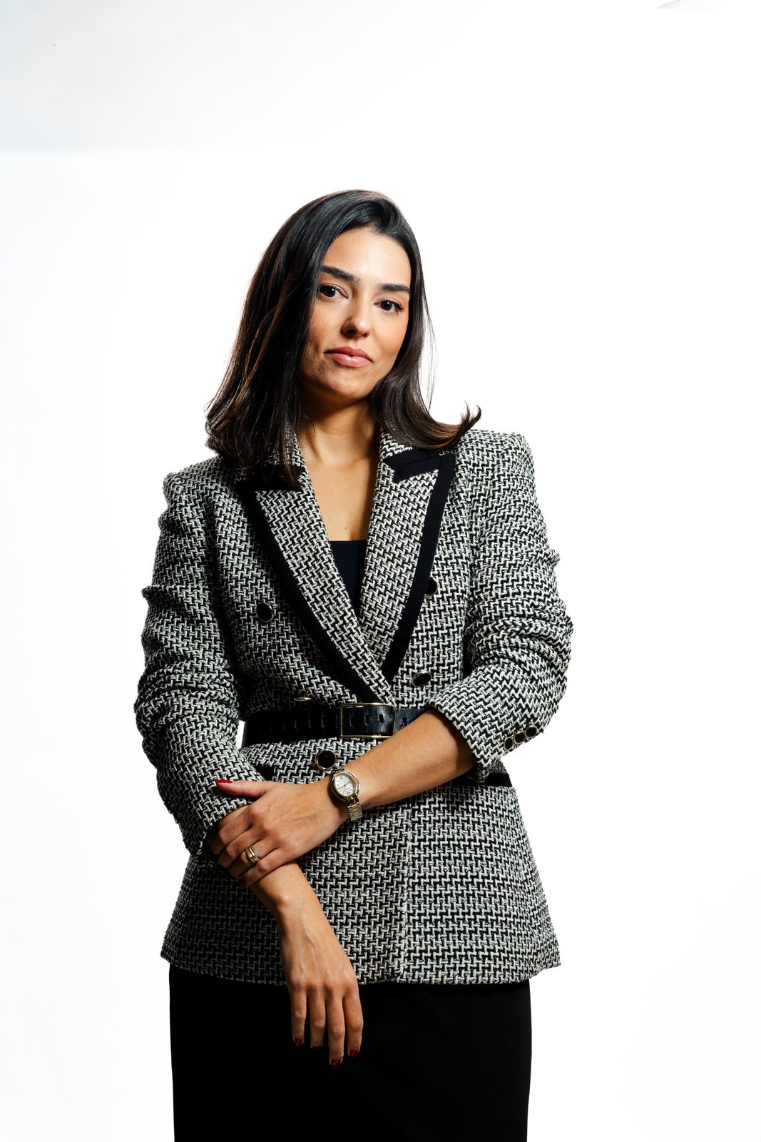 Thaís Dal Piaz, de blazer, braços cruzados, em estúdio com fundo branco